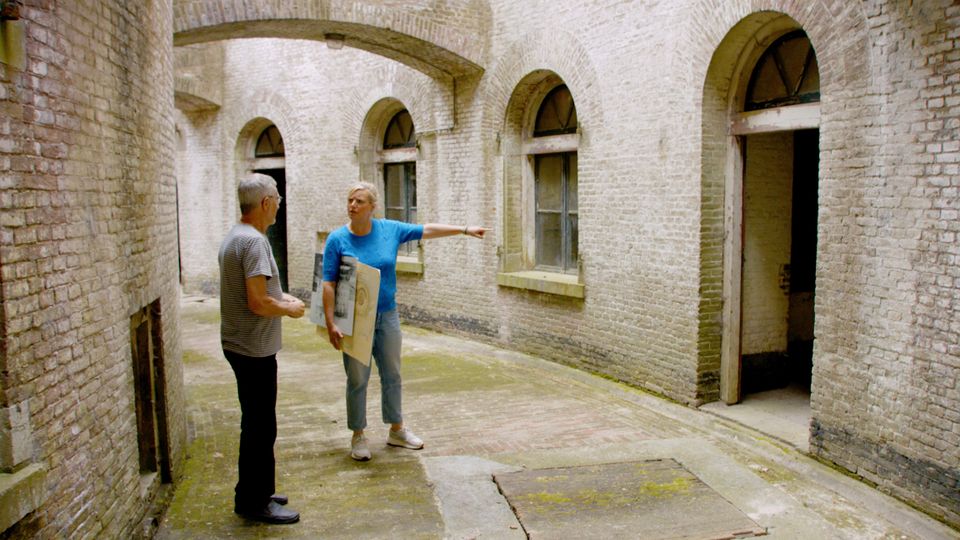 Een man en een vrouw lopen in een gang rond een bakstenen torenfort.