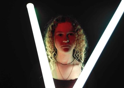 Jongere tussen lichtbuizen tijdens een creatieve activiteit in Het Klooster in Woerden.