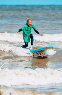 Een meisje die in de zee aan het golfsurfen is, in een wetsuit