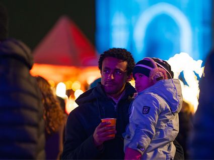 Vader kijkt samen met zijn kind naar de show tijdens Lichtjesavond in Delft