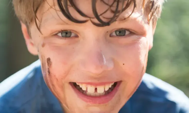 Lachende jongen die in de modder heeft gelegen.