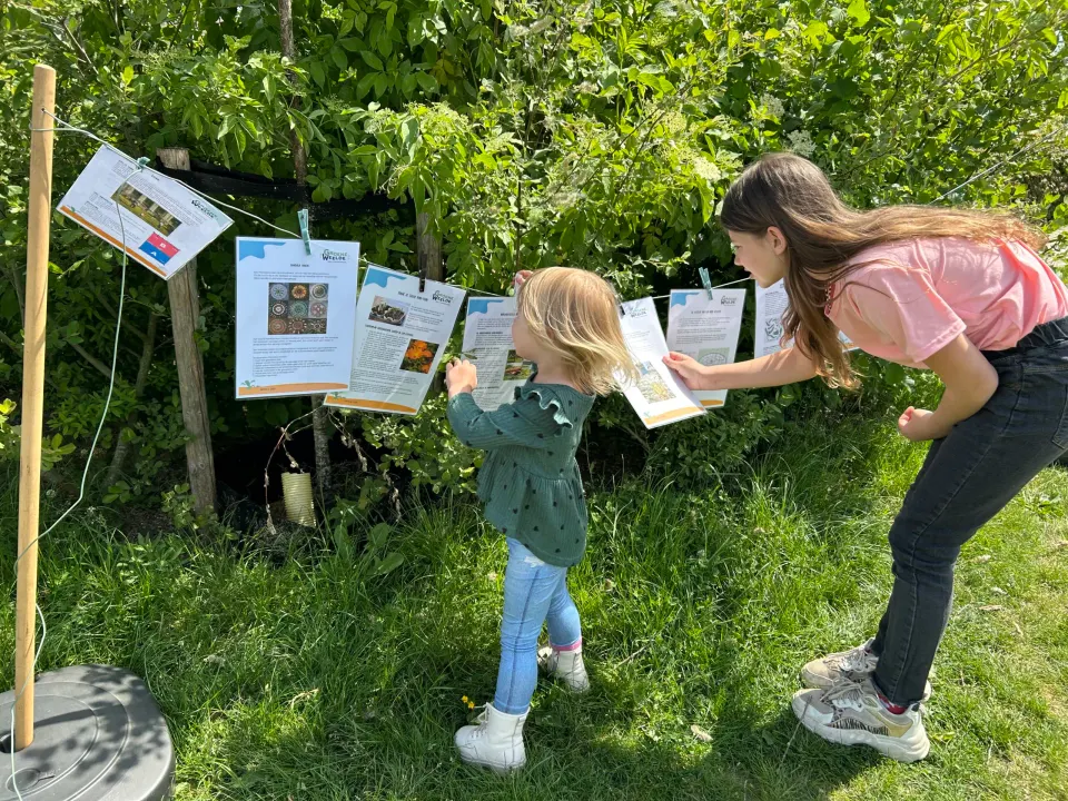 Twee kinderen kijken naar bedrukte papieren aan een waslijn