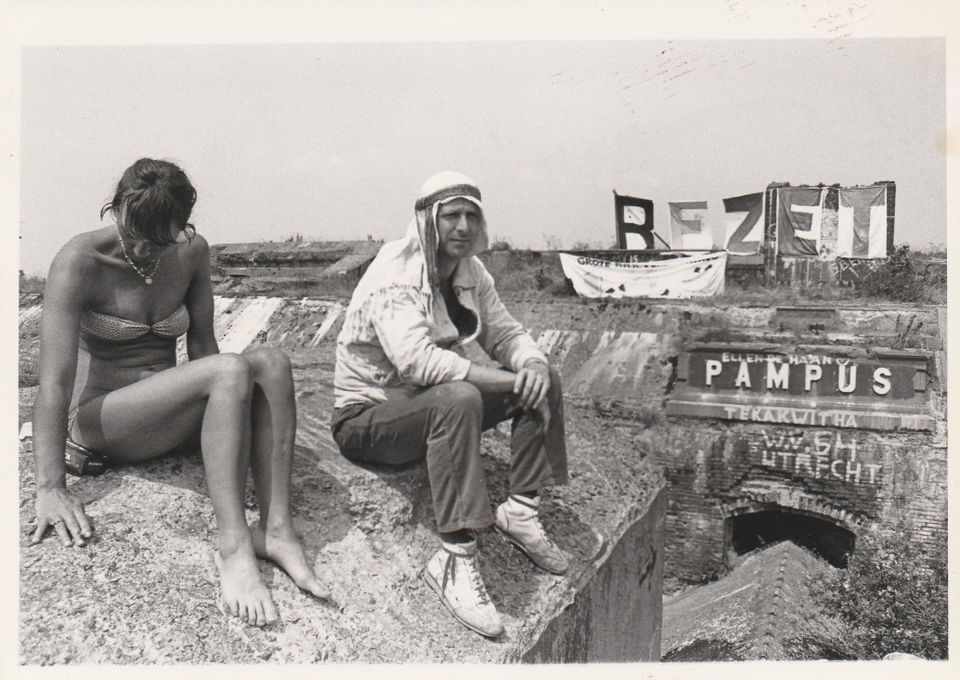 Zwart-wit foto van een man en een vrouw op pampus, met op de achtergrond spandoeken met 'Bezet' erop.