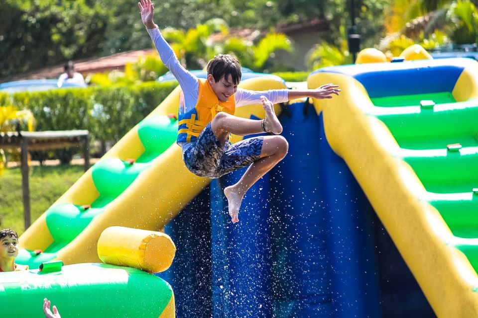 "Ein Junge springt von einem Spielgerät ins Wasser."