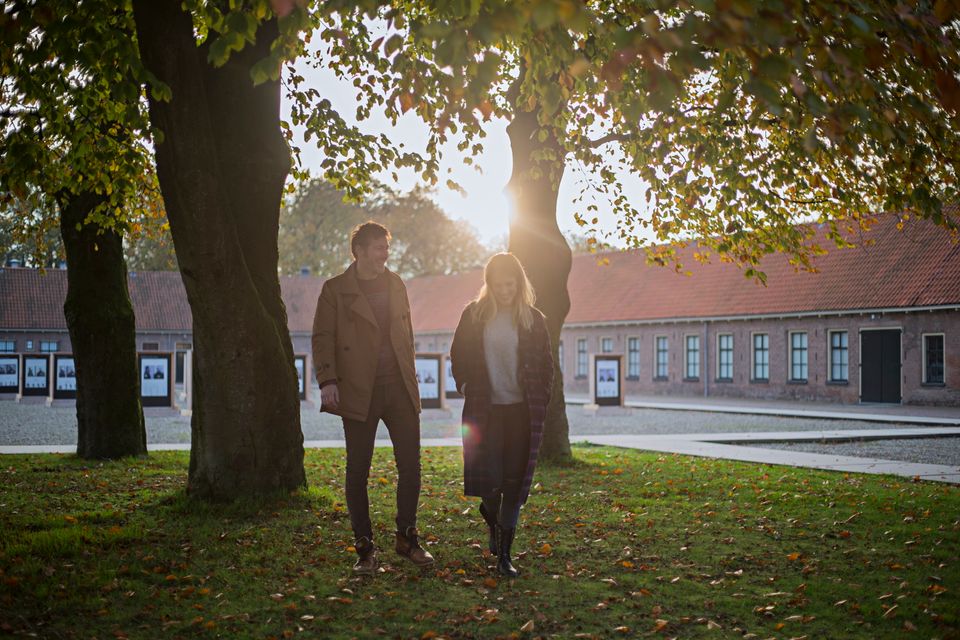 Een stel loopt bij het Gevangenismuseum onder de bomen door in de herfst.