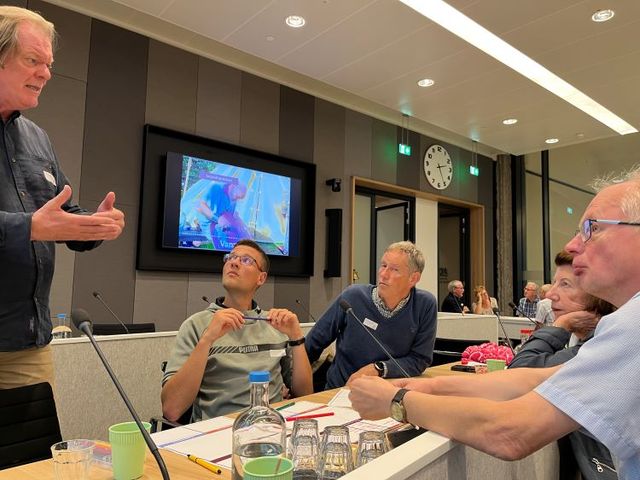 Groepje mannen rondom een tafel druk in gesprek