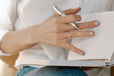 De hand van een vrouw slaat een bladzijde om in een notitieboek