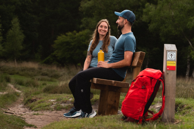 Ein Paar macht während einer Wanderung eine Pause auf einer Bank.