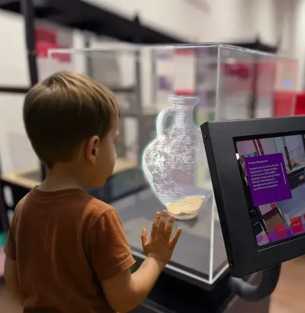 Een kind kijkt naar een 3D reconstructie van een Romeinse vaas