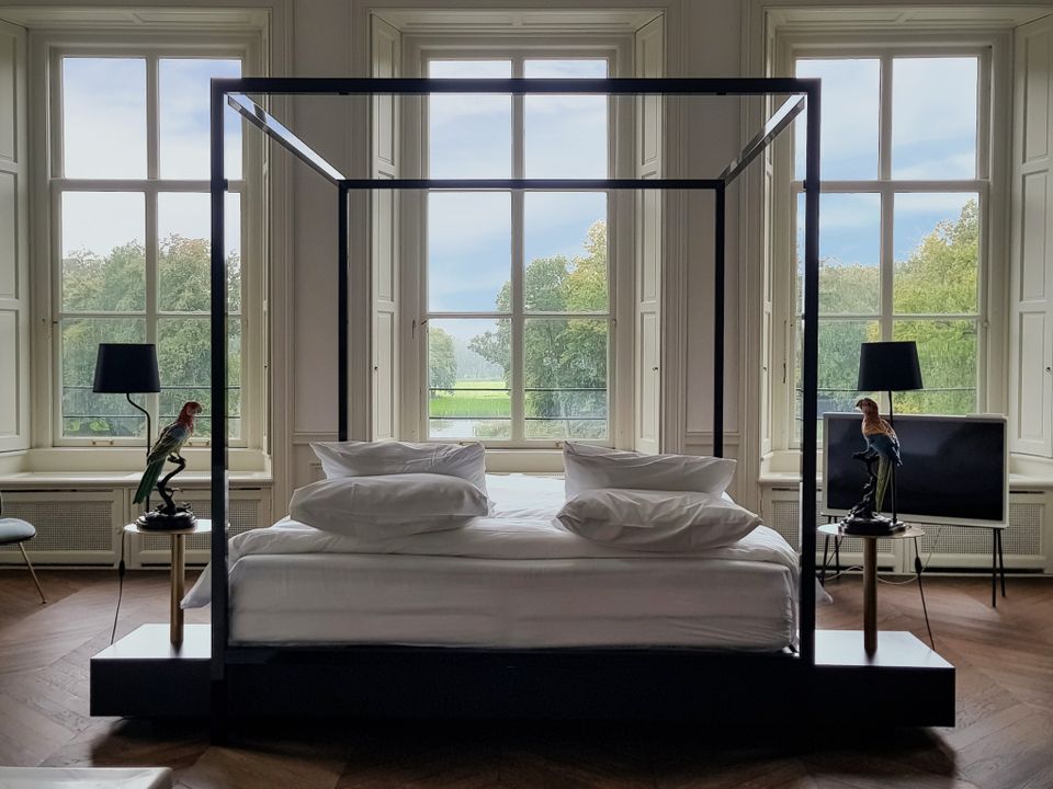De Grand Suite in Parc Broekhuizen met een bed dat uitkijkt op de Kasteeltuinen