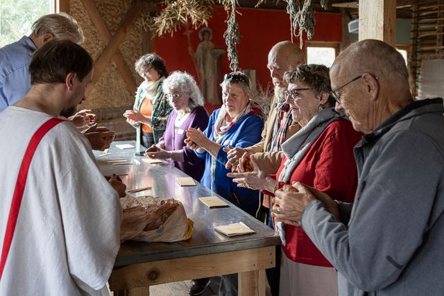 Deelnemers aan een statafel met een klompje klei, om zelf een aardewerken kommetje te maken.