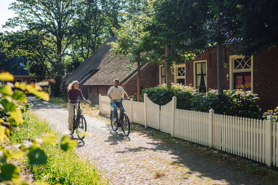 Ein Paar radelt durch ein Drenther Dorf.