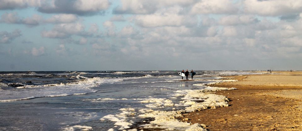 Surfers in schuim op strand
