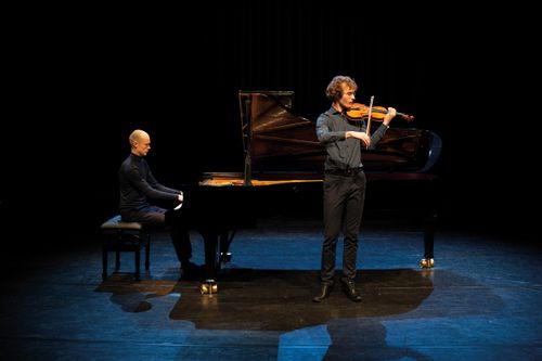 Een man achter de piano en een man met een viool