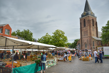 Gezellige streekmarkt in het centrum van Woerden met marktkramen en de Petruskerk op de achtergrond.
