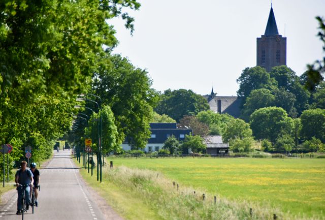 Mensen fietsen langs de weilanden rondom Soest met het centrum van Soest op de achtergrond
