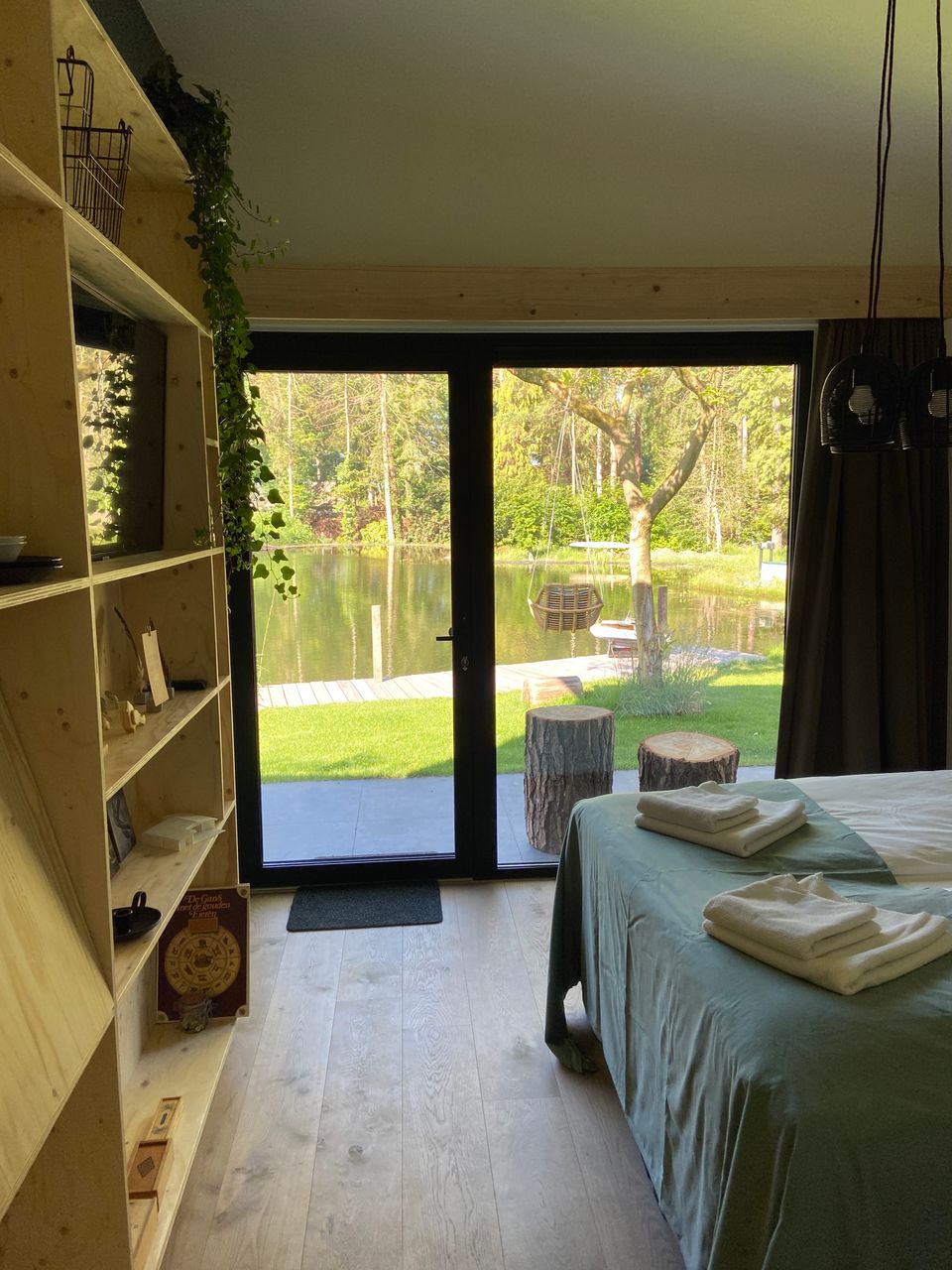 Slaapkamer met uitzicht op de vijver en een houten kast aan de linkerkant.