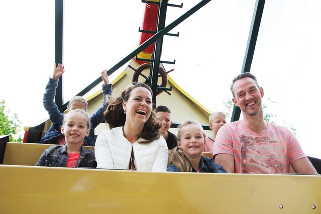 Een gezin zit in een piratenschip in een attractiepark.