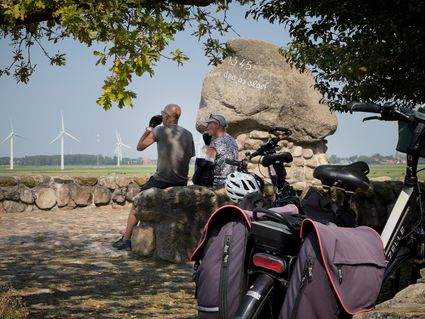 Twee fietsers rusten uit op een muurtje bij het Rode Klif bij Warns.