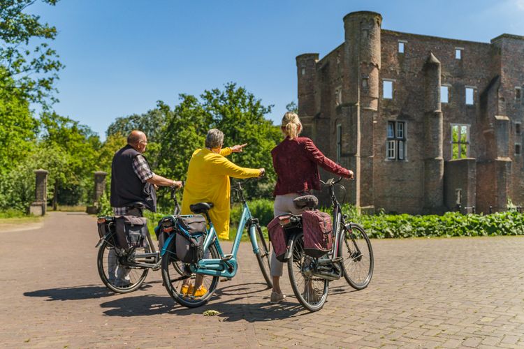 Drie fietsers kijken naar een kasteel.