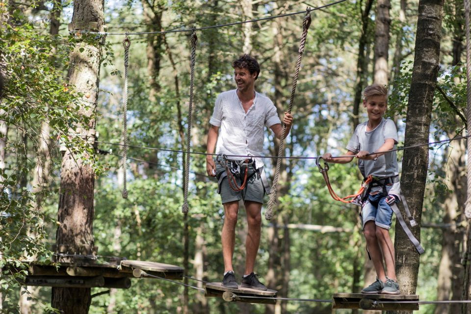 Vater und Sohn klettern in einem Kletterwald.