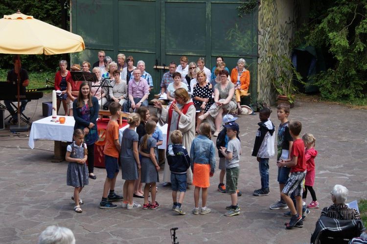 Kinderen en volwassenen die samen in het Natuurtheater Oisterwijk een Pinksterviering hebben.