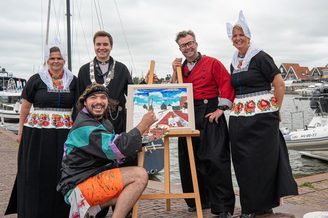 Een schilder met mensen in klederdracht bij een schilderij