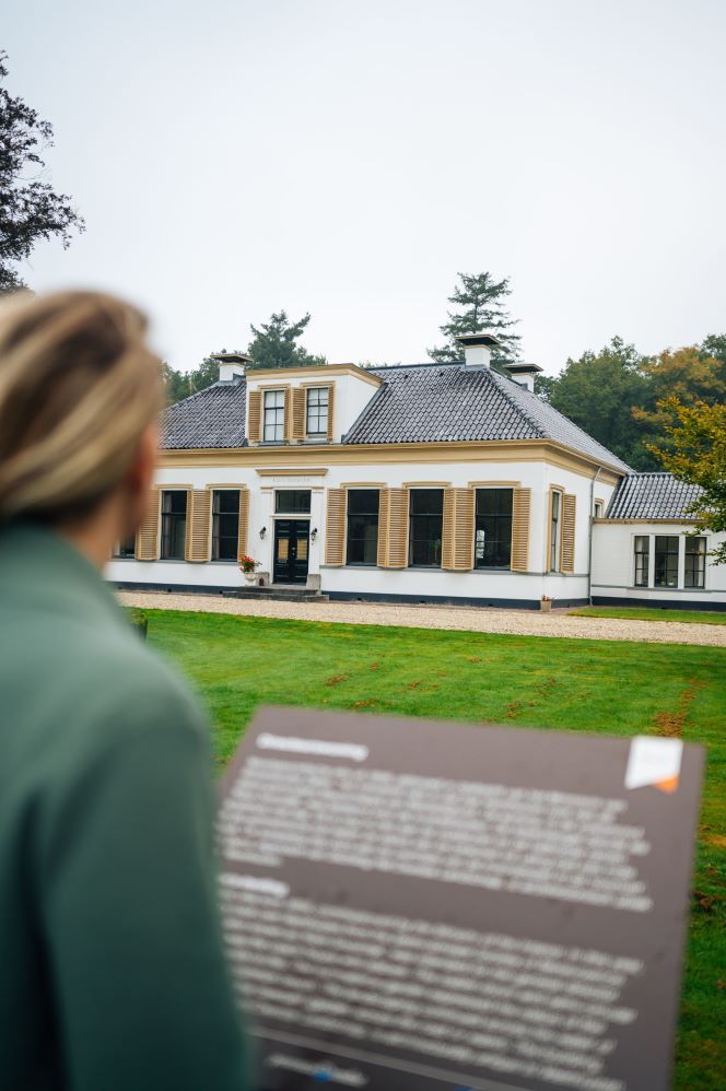 Een vrouw leest een informatiebord voor een huis