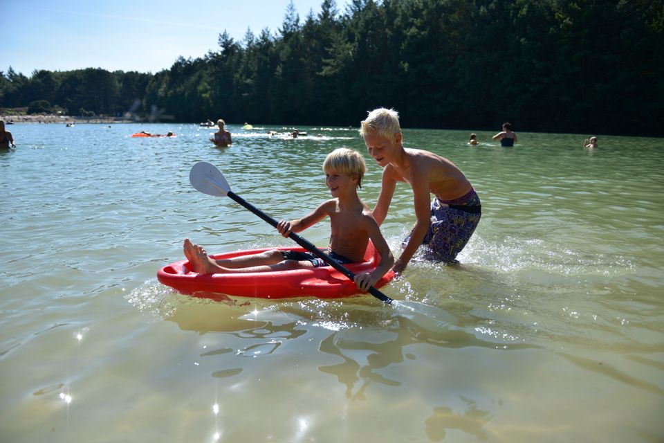 Jungen spielen mit einem kleinen Kanu im Wasser.
