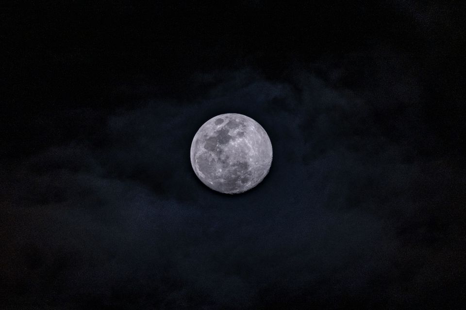 Volle maan aan een donkere hemel met wolken, passend bij de Nacht van de Nacht en de avondwandeling op Landgoed Bredius in Woerden.
