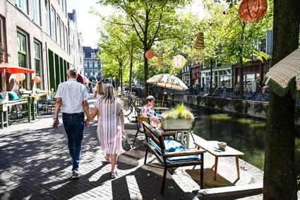 Ouder stel loopt langs het terras van 't Postkantoor in Delft in de zomer