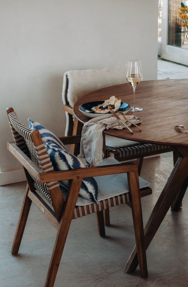 Houtel tafel en stoelen binnen in restaurant met blauwe en beige kussens en plaids