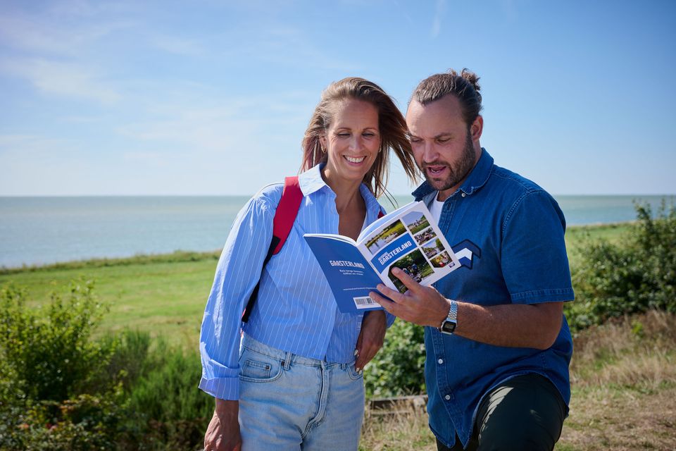 Twee mensen kijken in de Reisgids Gaasterland met op de achtergrond het IJsselmeer.
