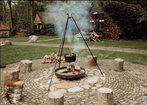 Ein Topf über einem Lagerfeuer auf dem Campingplatz, umgeben von Sitzgelegenheiten.