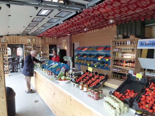 Landwinkel Kersenboomgaard en Boerderijwinkel De Ooievaar, Harmelen, provincie Utrecht, Groene Hart, interieur met vers fruit, groente, aardbeien, jam en streekproducten terwijl een klant afrekent bij de toonbank.