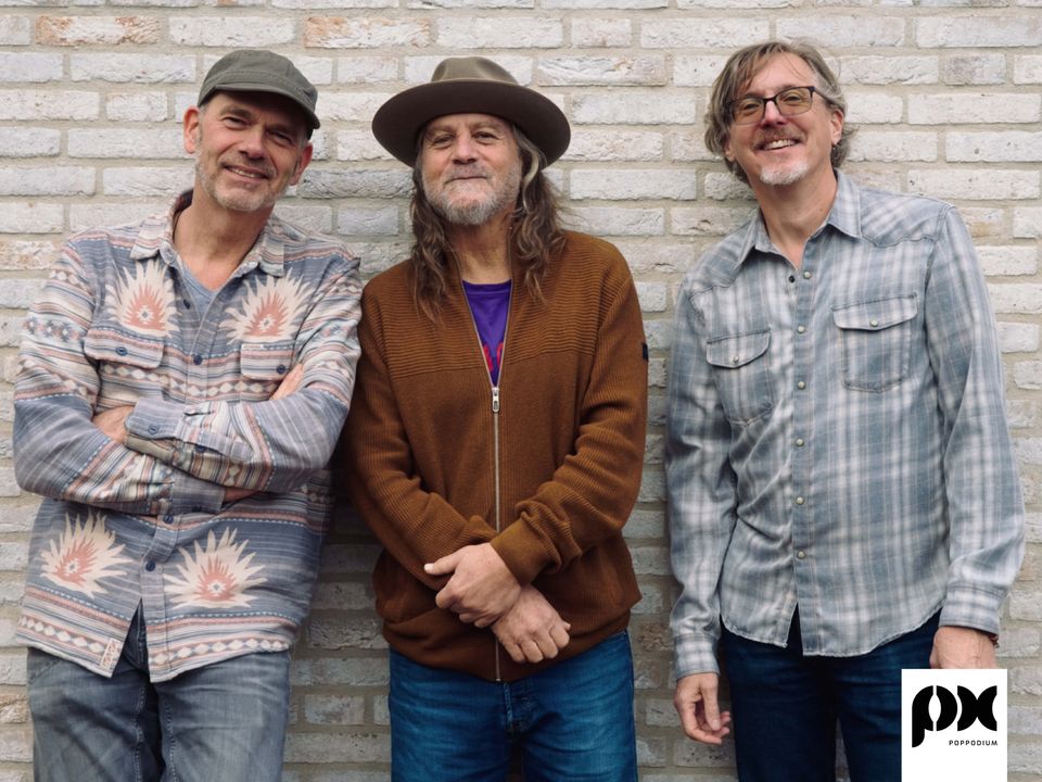 Drie mannen die tegen een muur staan