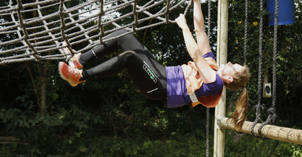 Meisje op de kop aan touwen tijdens survivalrun