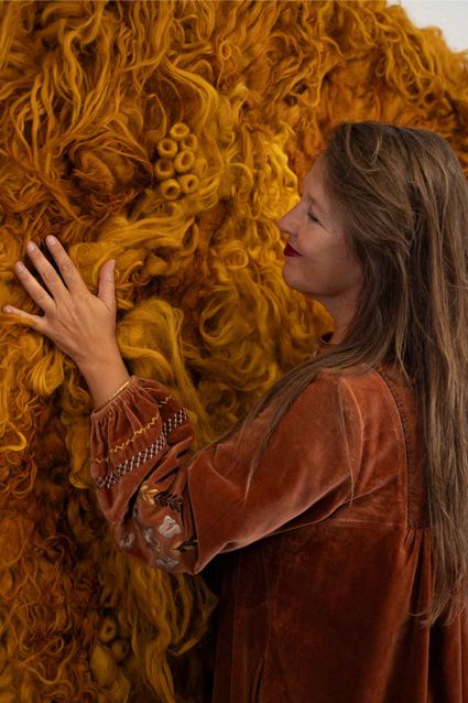 Momoko voor een door haar handgemaakte wolsculptuur die natuurgeverfd is met een reststroom van uischillen.