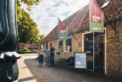 Museum Touwmuseum Oudewater in Oudewater, Groene Hart. Historisch museum over touwslagerij en touwproductie met bezoekers en fiets voor de entree van het karakteristieke monumentale pand in de binnenstad.