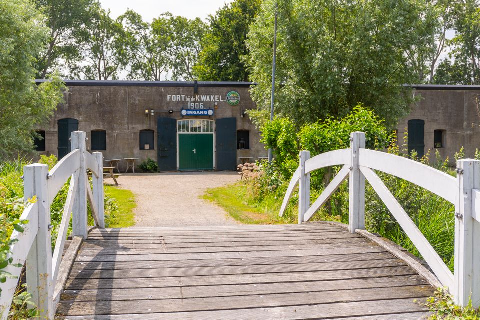 Een betonnen fort, gefotografeerd vanaf de overzijde van een houten brug.