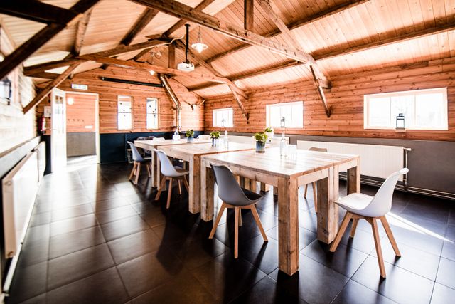 Sfeervolle vergader- en groepsruimte De Boerenzwaluw bij Aaltje aan de Linie in Woudenberg, ingericht met houten tafels, moderne stoelen en een warme landelijke uitstraling. De foto laat een rustige locatie zien voor vergaderen, bijeenkomsten en groepsactiviteiten.