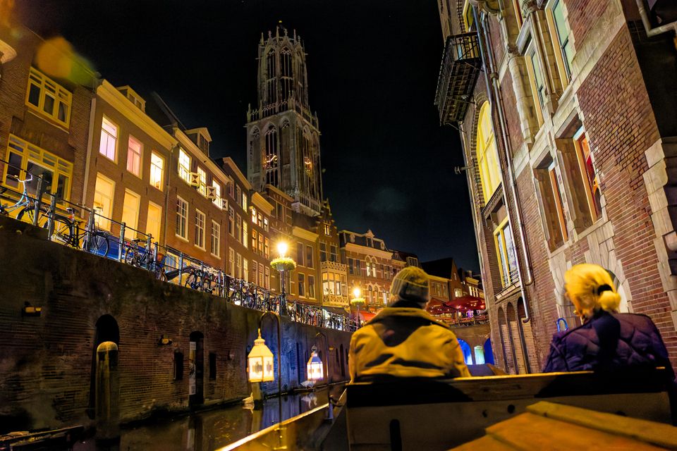 Twee mensen op het schip de Meern 1 's avonds, met mooie verlichting en de Domtoren.