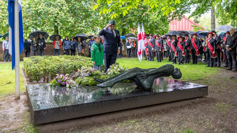 een militair brengt een saluut bij de kranslegging bij het beeld van de gevallen mens