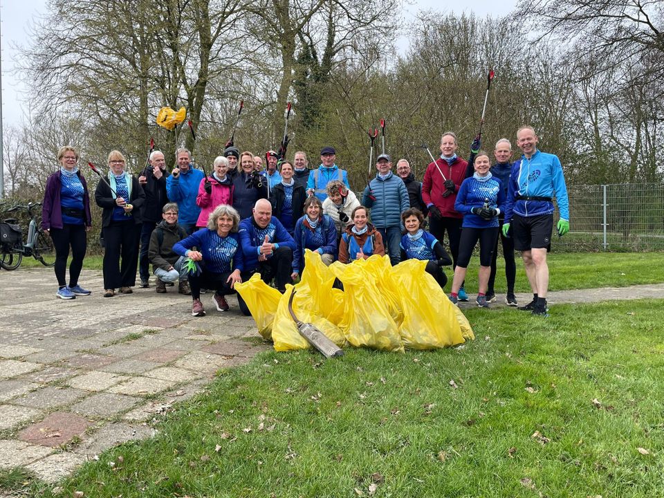 Groep vrijwilligers ruimt samen zwerfafval op tijdens een opruimactie in Woerden. Op de voorgrond liggen gevulde gele afvalzakken.