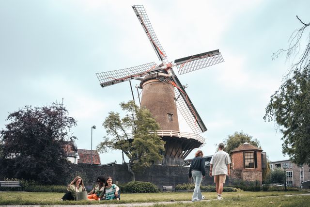 Historische korenmolen De Windotter IJsselstein, Groene Hart, monumentale windmolen met draaiende wieken, bezoekers wandelen en ontspannen in het groene stadspark aan de voet van de molen.