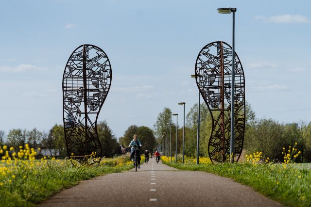 Der Fußabdruck des Kunstwerks, zwei große Stahlschuhe auf einem langen Fahrradweg.