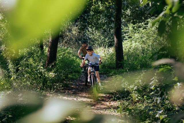 Vader en kind met moutainbike door het bos