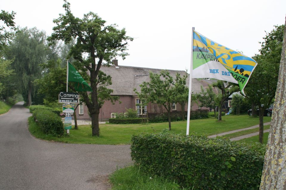 Boerderijcamping Bij Groen Geluk, Hekendorp, landelijk dorp aan de Lek, Groene Hart, groene camping met boerderij, vlaggen en oprijlaan in een rustig polderlandschap.
