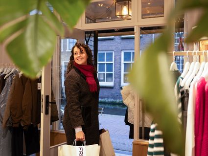Een dame die een winkel in Delft uit loopt