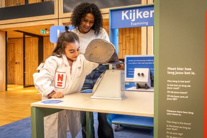 Een kind onderzoekt een dino-bot in Naturalis.